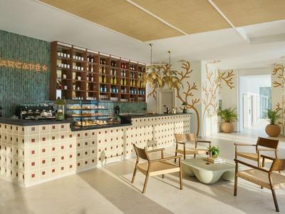 Nowoczesna lobby hotelowa z barem, drewnianymi meblami i jasną, przyjazną atmosferą.