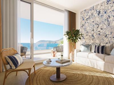 Helles Wohnzimmer mit Sofa, Stuhl und Blick auf Meer und Felsen durch große Fenster