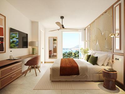 Helles Hotelzimmer mit Doppelbett, Schreibtisch, Fernseher und Balkon mit Meerblick.