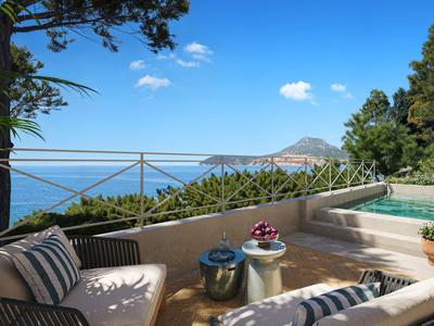 Terrasse mit gemütlichen Sitzgelegenheiten, Pool und Blick auf das Meer und Berge.