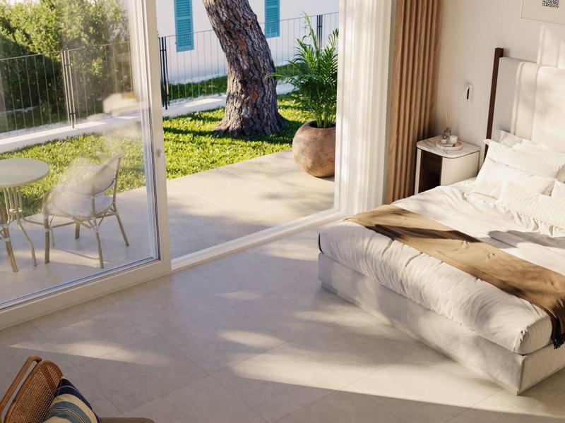 Gemütliches Schlafzimmer mit großen Fenstern und Blick auf Garten und Terrasse.