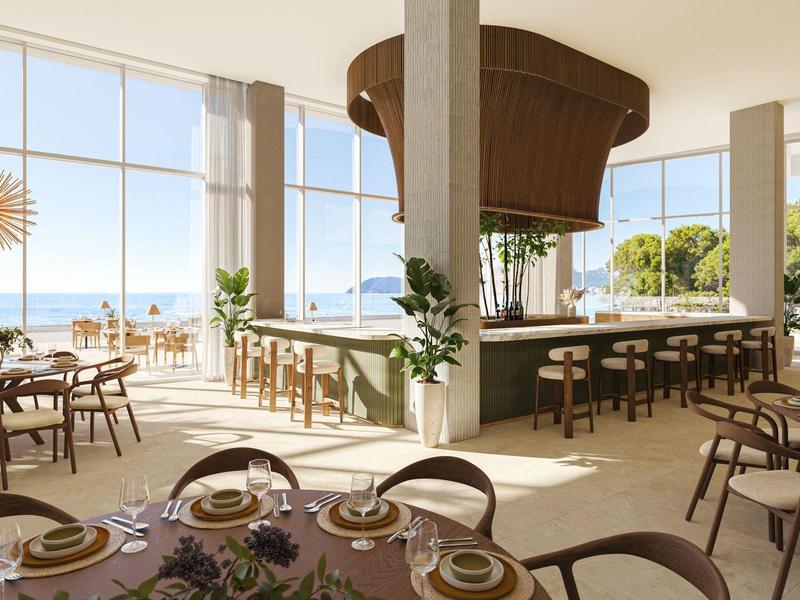 Helles Restaurant mit großen Fenstern, Rundbar und Blick aufs Meer.