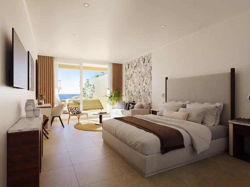 Modernes Hotelzimmer mit großem Bett, Sitzbereich und Balkon mit Meerblick.