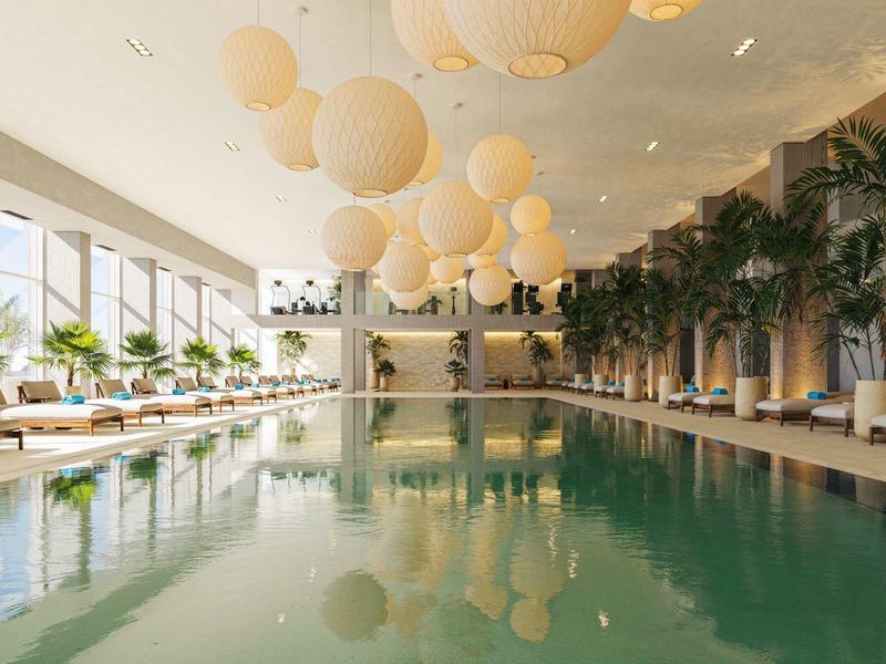 Eleganter Innenpool mit Hängelampen, Pflanzen und Liegen in hellem Wellnessbereich.