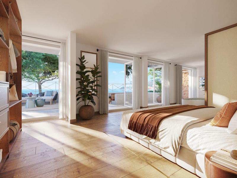 Helles Hotelzimmer mit Doppelbett, Holzmöbeln und Zugang zu einer Terrasse mit Blick aufs Meer.