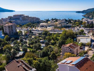 Blick auf eine Küstenstadt mit Gebäuden, Bäumen und Bergen am Horizont.