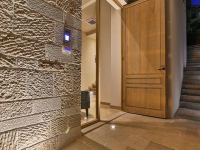 Illuminated house entrance with open wooden door and indoor stairs