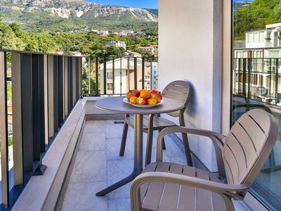 Balkon mit zwei Stühlen und Tisch mit Obstschale vor Bergkulisse.