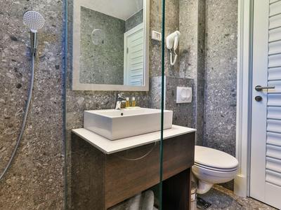 Modernes Badezimmer mit eckiger Waschschüssel, Glastrennwand und WC neben einer weißen Tür.