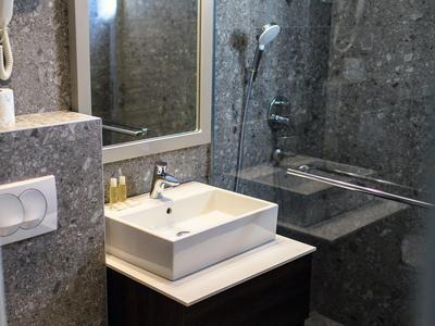 Modernes Badezimmer mit quadratischem Waschbecken, Toilette und begehbarer Dusche mit Glaswand.