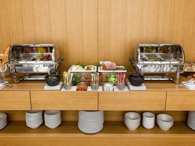 Buffet mit Aufschnitt, Obst und Snacks auf einem langen Holztisch vor einer Holzverkleidung.