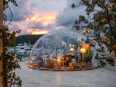 Glaskuppel auf Terrasse mit Sitzplatz und Meerblick bei Sonnenuntergang.