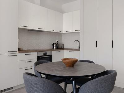 Balkon mit Metallgeländer, Tisch und Stühlen mit Blick auf Bäume und Gebäude.