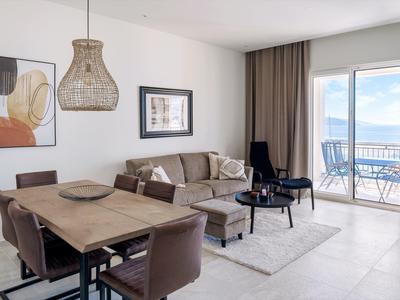 Modern eingerichtetes Wohnzimmer mit Essbereich und Balkonblick auf Meer