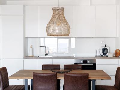 Moderner Essbereich mit Holztisch, sechs Stühlen und heller Küchenzeile im Hintergrund.