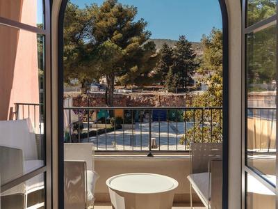 Balkon mit runden Tisch und zwei Stühlen, Blick auf Bäume und blauen Himmel.