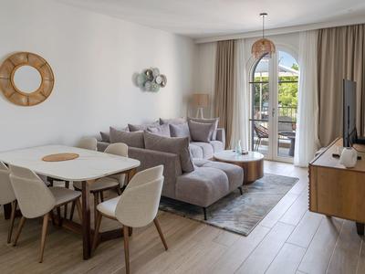 Helles Wohnzimmer mit Sofa, Esstisch, TV und Zugang zu einem Balkon mit Außenblick.