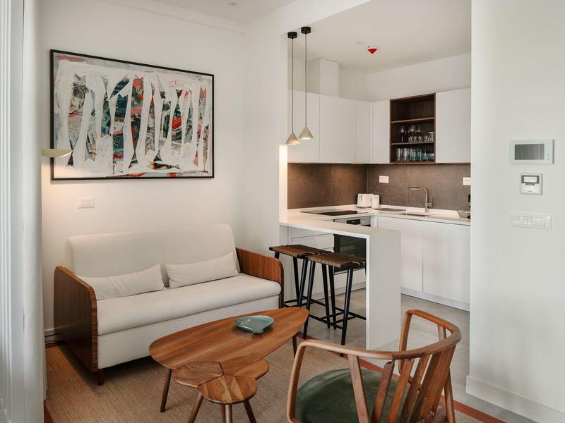 Moderner Essbereich mit Holztisch, sechs Stühlen und heller Küchenzeile im Hintergrund.