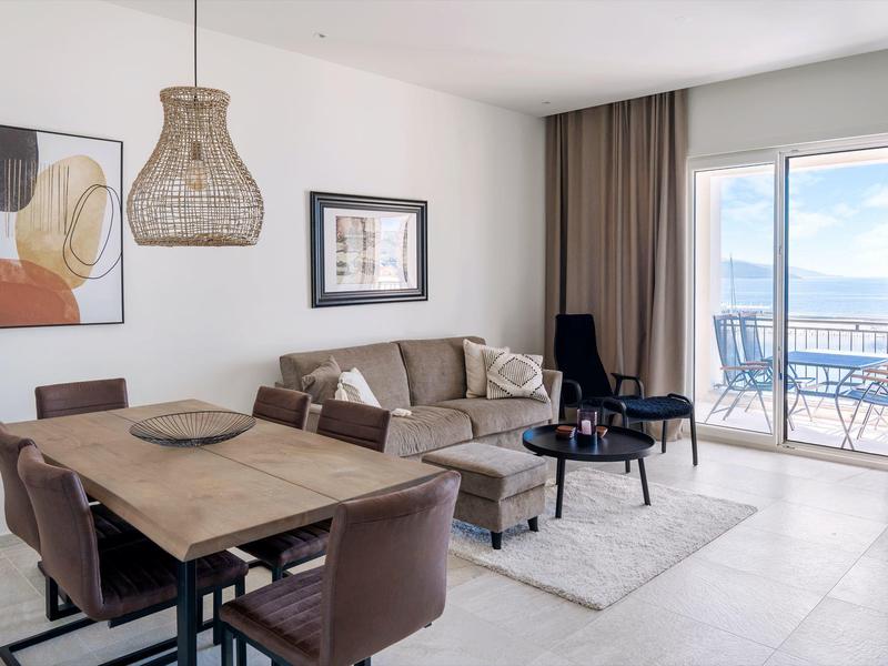 Modern eingerichtetes Wohnzimmer mit Essbereich und Balkonblick auf Meer