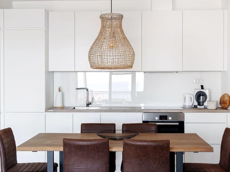 Moderner Essbereich mit Holztisch, sechs Stühlen und heller Küchenzeile im Hintergrund.