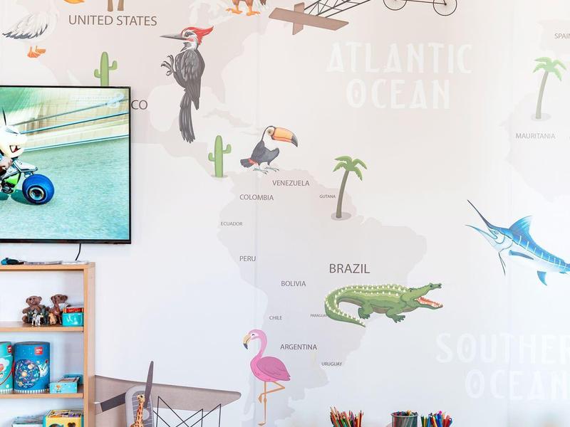 Kinderzimmer mit Weltkartenwand, Spielzeug, grünem Sitzsack und buntem Mobiliar