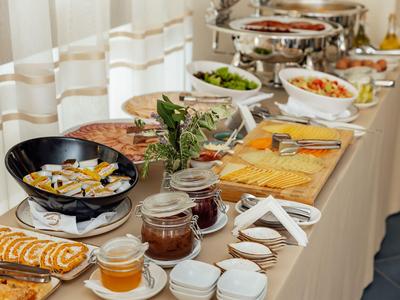 Buffet con vari piatti e barattoli su un tavolo apparecchiato in una stanza luminosa.