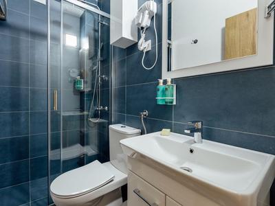Bagno compatto con doccia, toilette, lavandino e specchio a parete in tonalità moderne di blu.