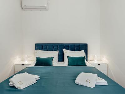 Camera da letto moderna con letto blu, cuscini, asciugamani bianchi e arredamento minimalista.