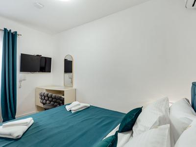 Camera d'hotel moderna con letto blu, TV a parete e piccolo specchio.