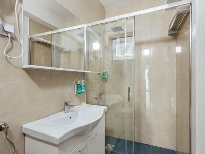 Bagno moderno con lavabo, specchio e doccia in vetro dai toni neutri.