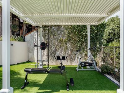 Area esterna coperta con attrezzature per il fitness su prato artificiale verde in un ambiente alberghiero.