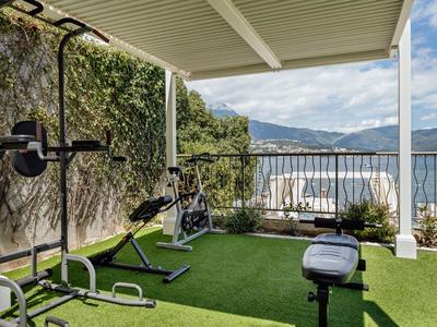 Area palestra all'aperto coperta con attrezzature e vista sul mare