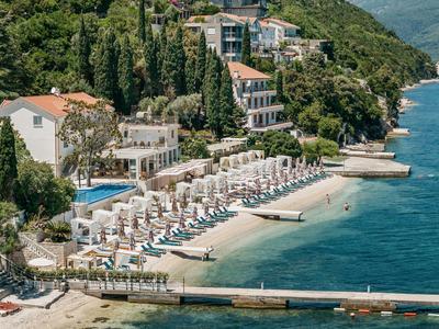Hotel sulla spiaggia su una collina boscosa con lettini, ombrelloni e acqua limpida e blu
