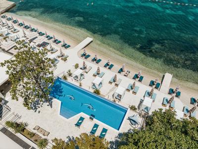 Piscina moderna con lettini e vista sulla spiaggia e sul mare.
