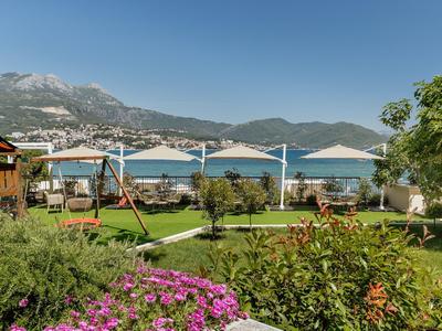 Giardino con ombrelloni, parco giochi e vista sulla montagna in una giornata di sole