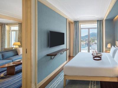 Moderndes Hotelzimmer mit Doppelbett, TV, Sofa, Spiegel und Fenster mit Bergblick.