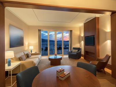 Gemütliches Wohnzimmer mit Sofa, Couchtisch und großen Fenstern zum Balkon bei Abendlicht.