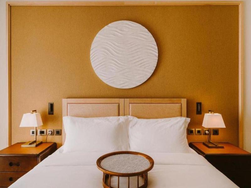 Modernes Schlafzimmer mit weißem Bett, zwei Nachttischen, Lampen und rundem Wanddekor.