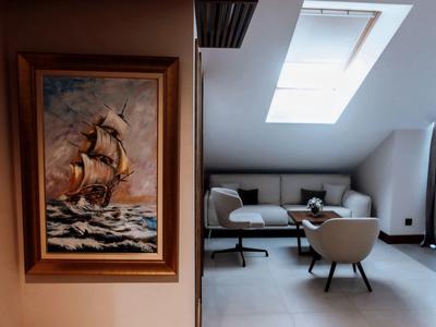 Gemälde eines Segelschiffs an einer Wand neben einem modernen Sitzbereich mit Sofa und Stühlen