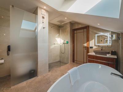 Modernes Badezimmer mit freistehender Badewanne, Dusche und großen Spiegeln in hellem Design.