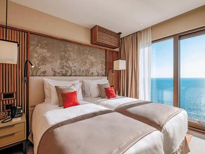 Hotelzimmer mit zwei Einzelbetten und Meerblick durch große Fenster