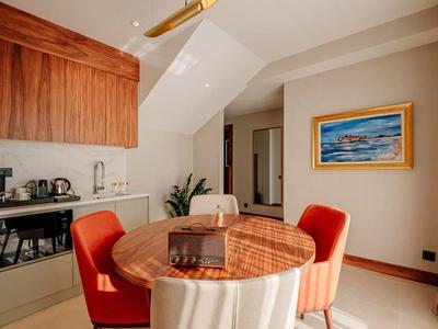 Moderner Essbereich mit rundem Tisch, roten Stühlen und Küchenzeile unter einer Dachschräge.