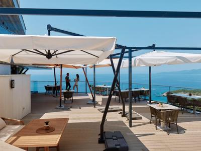 Moderne Terrasse mit Sonnenliegen und Sonnenschirmen mit Blick auf das Meer.