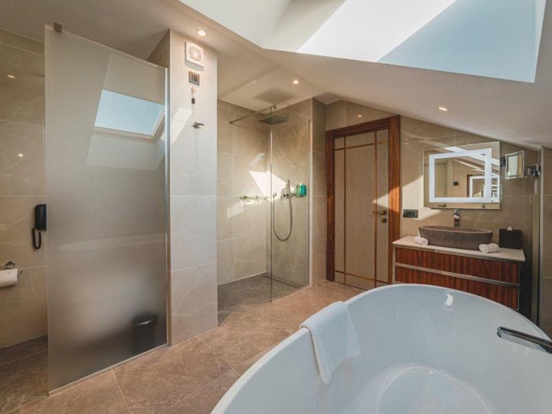 Modernes Badezimmer mit freistehender Badewanne, Dusche und großen Spiegeln in hellem Design.