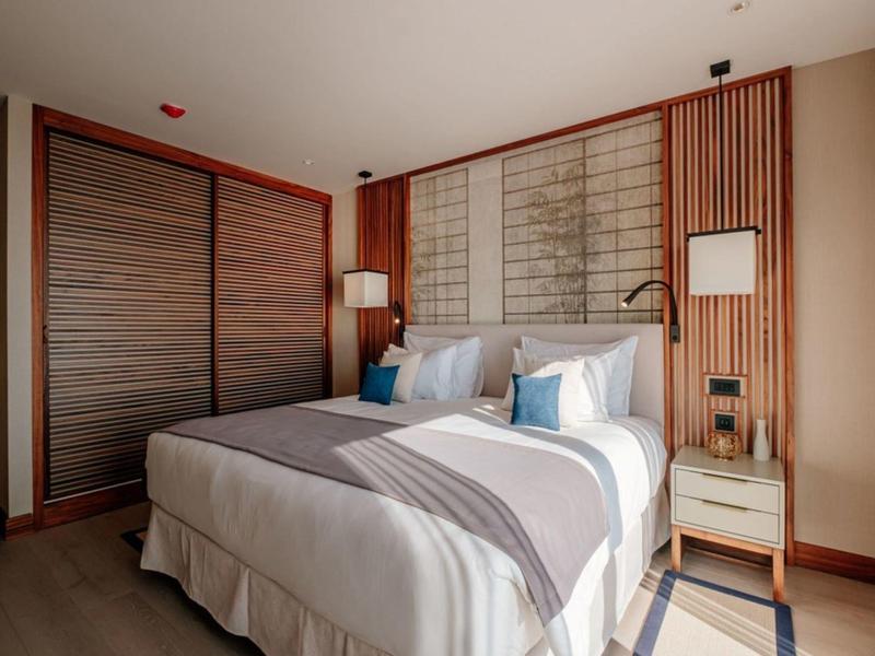 Modernes Hotelzimmer mit Doppelbett, Holzvertäfelung und sanfter Beleuchtung