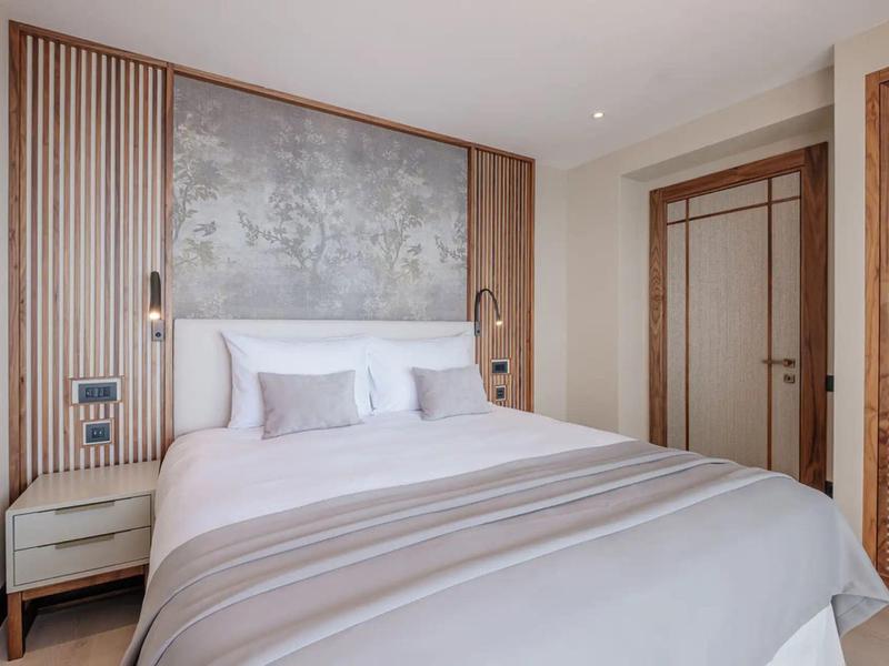 Modernes Hotelzimmer mit großem Bett, zwei Kissen und Holzvertäfelung an den Wänden.