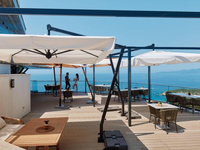 Moderne Dachterrasse mit Sitzbereichen und Meerblick an einem sonnigen Tag.