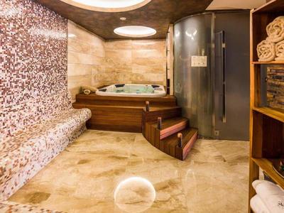 Moderner Wellnessbereich mit Whirlpool, Dampfbad und Mosaik-Sitzbank.