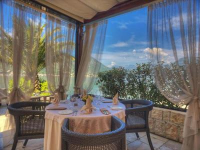 Área de comedor exterior cubierta con mesa, sillas y vista a una colina bajo cielo azul.