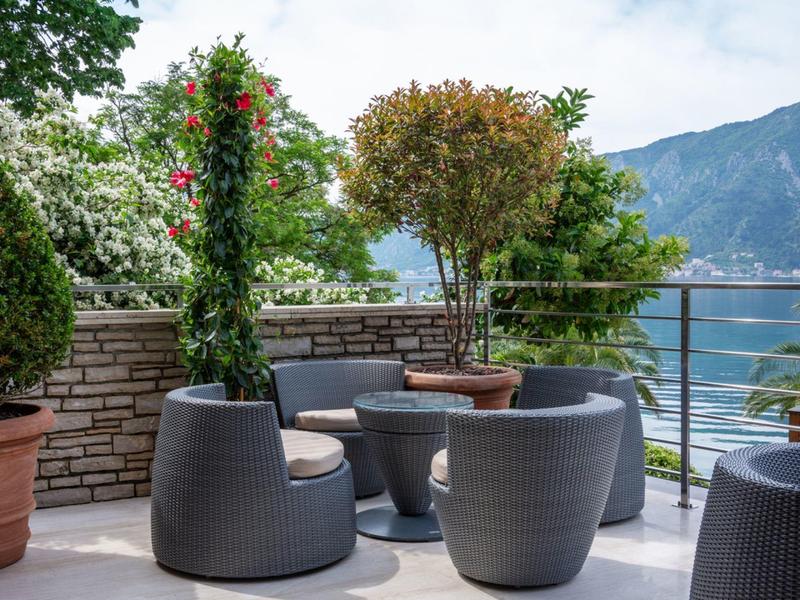 Terrasse mit runden Sitzmöbeln und Pflanzen mit Berg- und Seeblick